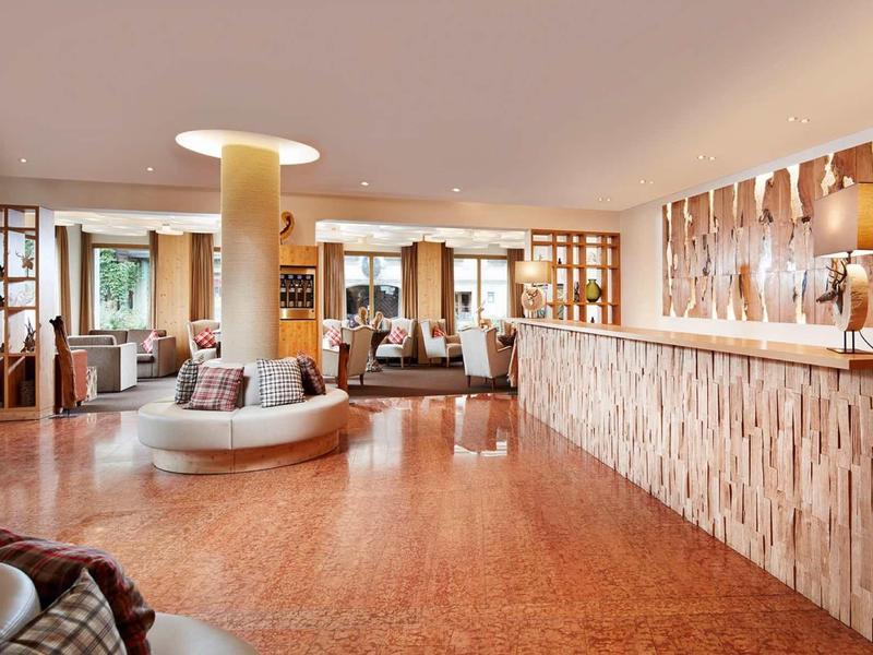 Elegante hall dell'hotel con banco accoglienza in legno moderno e aree salotto confortevoli.