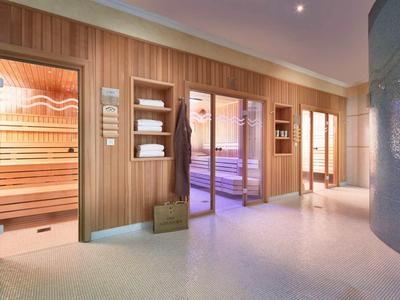 Lichte wellnessruimte met sauna en ontspanningsruimte, houten panelen en rustgevende verlichting.