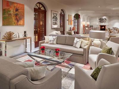 Een lichte, gezellige woonkamer met banken, fauteuils en een glazen tafel in een hotel.