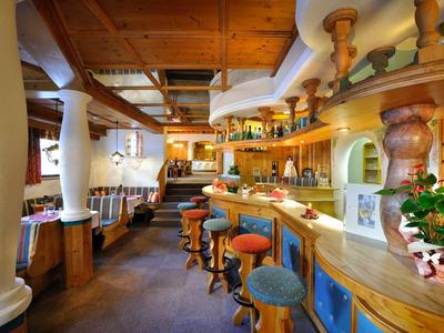 Gemütliche Hotelbar mit Holzmöbeln, Sitzhockern und warmem Licht.