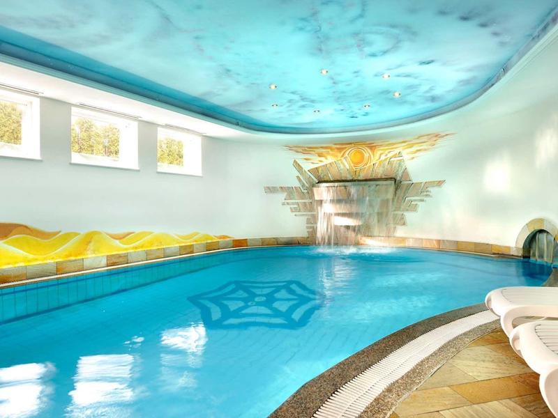Piscina interna luminosa con soffitto blu e comode sedie a sdraio