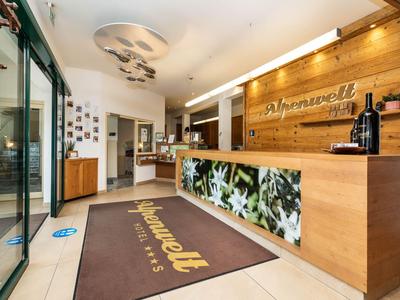 Heller Hotel-Empfangsbereich mit Holztresen, großem Teppich und moderner Dekoration.