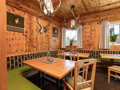 Gemütlicher Holzesstisch mit grünen Sitzpolstern in einem rustikalen Hotelzimmer.