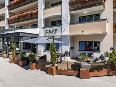 Außenbereich eines Cafés mit Sitzgelegenheiten und Sonnenschirm an einem Hotel.