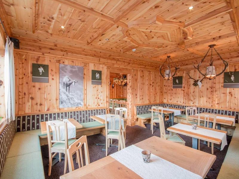 Przytulna rustykalna jadalnia z drewnianą boazerią i prostym umeblowaniem.