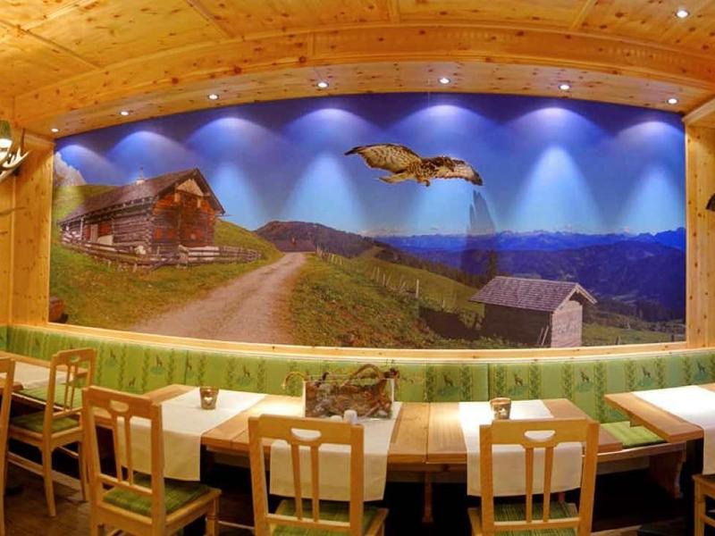 Przytulna jadalnia z drewnianymi meblami, dużym muralem krajobrazu górskiego i panoramicznym widokiem.