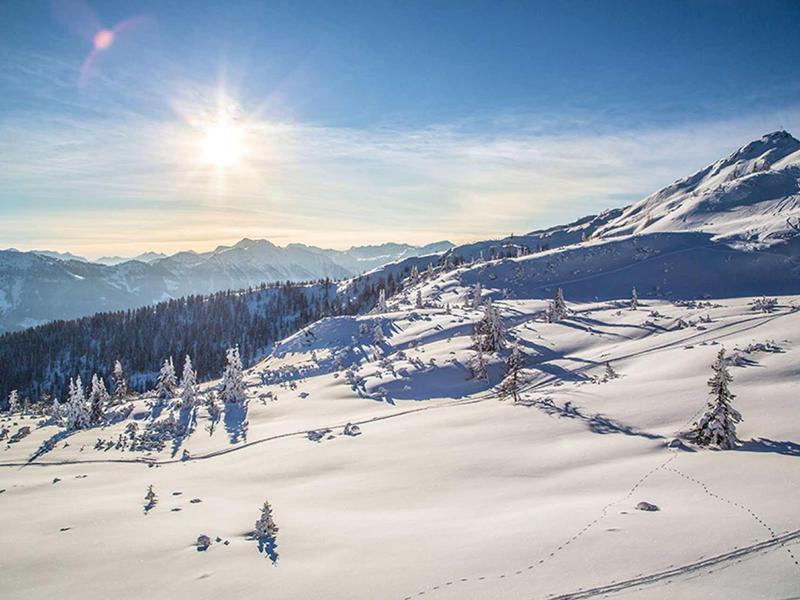 Zaśnieżony krajobraz górski z czystym niebem i jasnym słońcem podczas zimowych wakacji.
