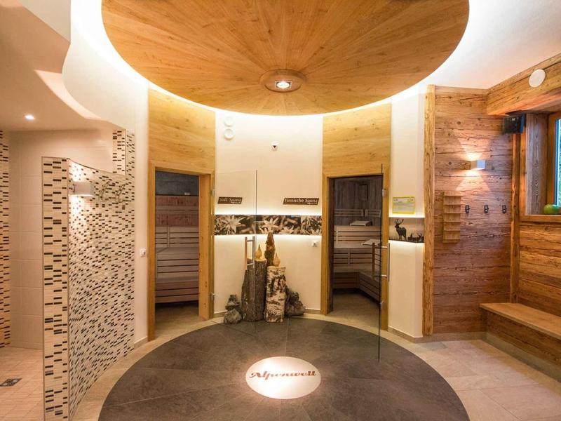 Nowoczesne pomieszczenie wellness z sauną, prysznicem i przytulną, drewnianą strefą relaksu.