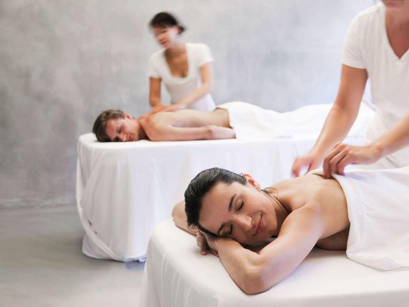Una pareja recibe un masaje en un spa tranquilo con camillas cómodas y luz tenue.