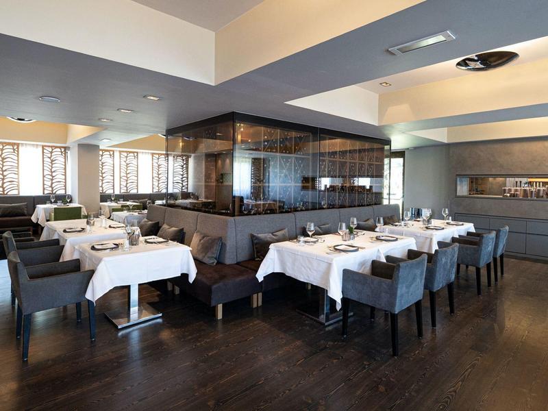 Interior elegante de restaurante con manteles blancos y sillas grises en un hotel moderno.