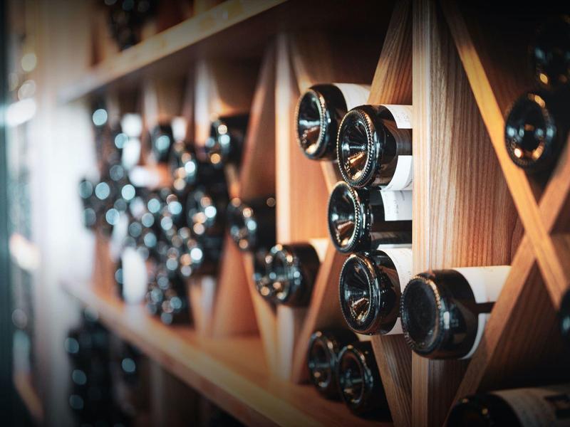 Estante de madera con botellas de vino almacenadas en ángulo en una bodega.