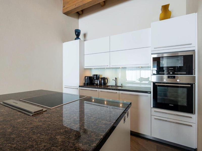 Modern kitchen with white cabinets, built-in oven, and granite countertop island.