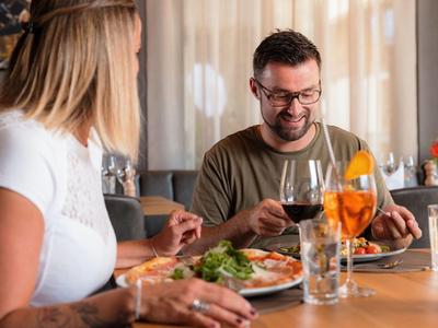 Pár sedí v restauraci a užívá si jídlo při útulném osvětlení.
