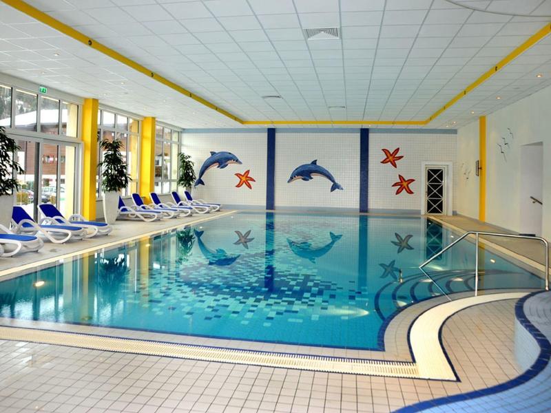 Vnitřní bazén s barevnými dekoracemi delfínů a mořských hvězd a modrými lehátky