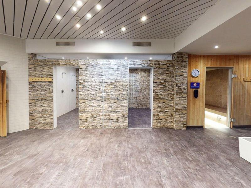 Moderní vstupní část hotelové haly se zdi z kamene a dřevěnými dveřmi.