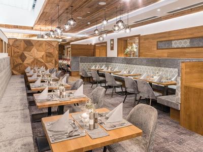 Ristorante elegante con tavoli in legno, sedie grigie e illuminazione moderna.