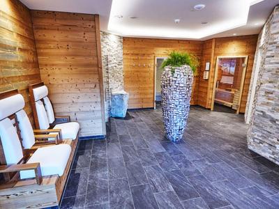 Modern hotel hallway with wooden walls, stone accents, and white cushioned wooden chairs.