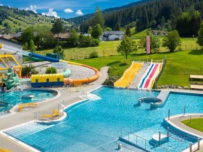 Large outdoor pool with water slides and green landscape in the background.