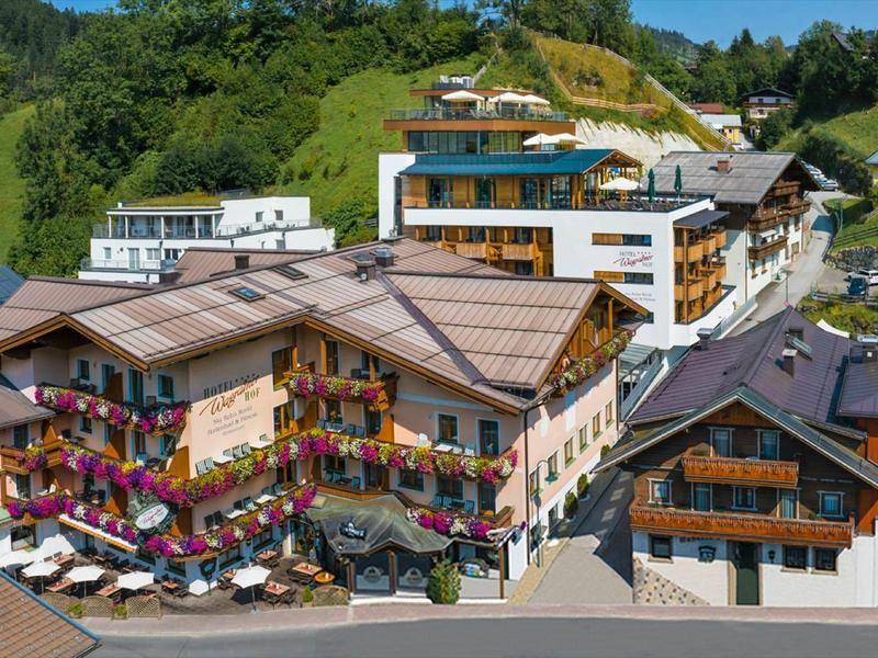 Mountain village with hotels, traditional chalets, outdoor areas, and flowers on balconies.