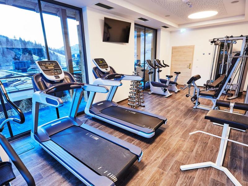 Bright gym with treadmills and strength machines, large windows with a view.