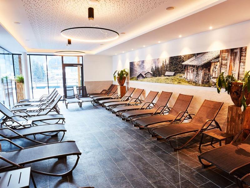 Modern relaxation room with lounge chairs and large plants in a hotel spa.