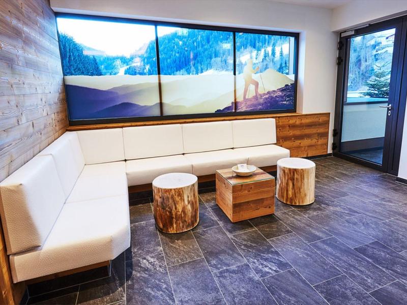 Modern seating area with white sofa, wooden stools, and alpine view on the wall.