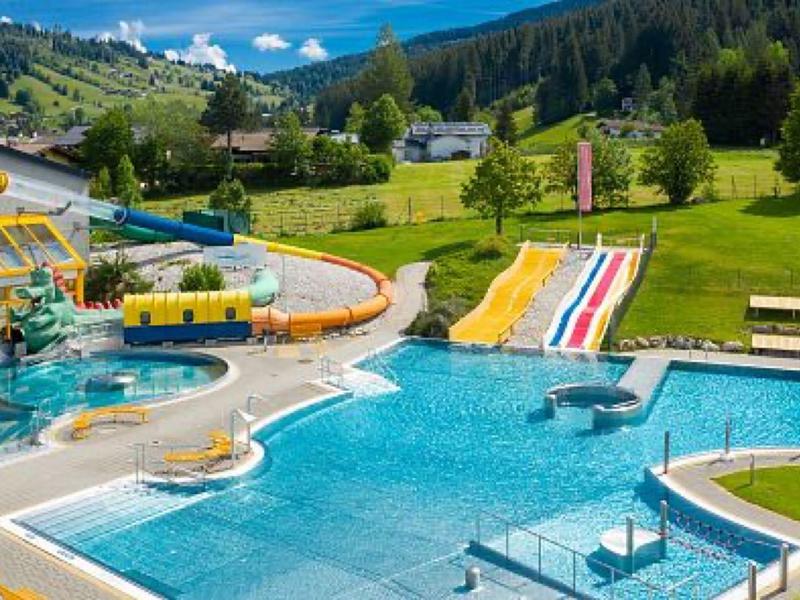Large outdoor pool with water slides and green landscape in the background.