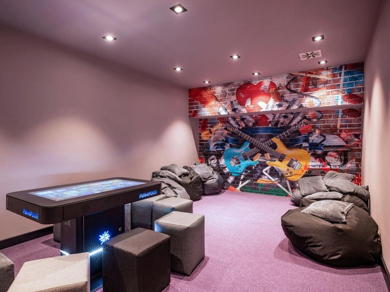 Room with colorful mural, bean bags, and interactive table in a hotel.