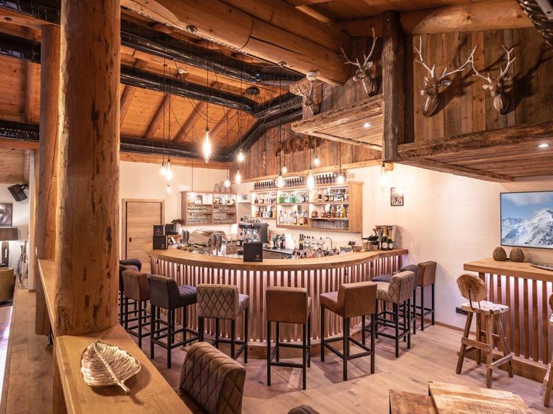 Rustic hotel bar with wooden counter, bar stools, and cozy atmosphere.