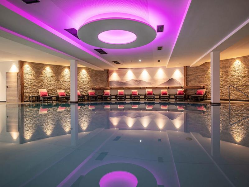 Elegant hotel pool with indirect lighting and modern ceiling lights in warm tones.