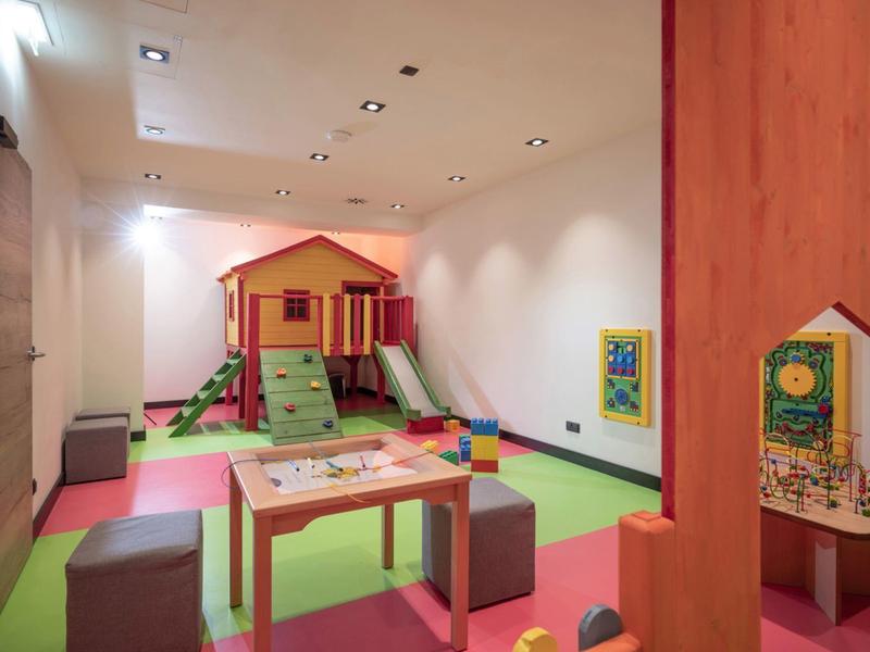 Indoor kids' play area with a hut, slide, table, and colorful cube seats.