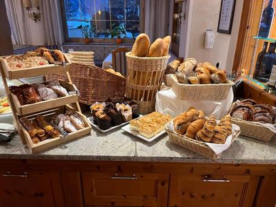 Verschiedene Brotsorten und Backwaren in Körben und auf Tabletts auf einer Marmorarbeitsfläche.