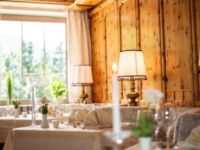 Elegantes Restaurant mit Holzwänden, weißen Tischdecken und warmem Lampenlicht.