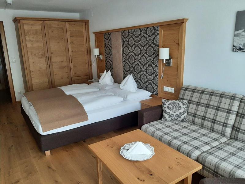 Gemütliches Schlafzimmer mit Doppelbett, kariertem Sofa, Holzmöbeln und Wandlampen.