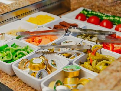 Buffet table with various vegetables, pickles, and small condiment containers.