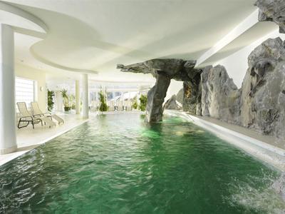 Indoor pool with rock features and lounge chairs in a bright, elegant space.