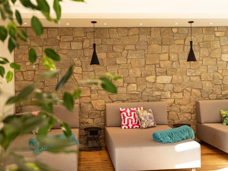 Modern lounge area with stone wall, pendant lights, and cozy seating with colorful cushions.