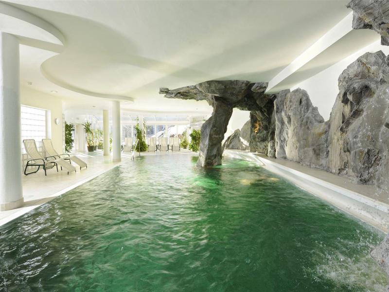 Indoor pool with rock features and lounge chairs in a bright, elegant space.