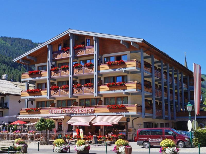 Ein mehrstöckiges Chalet mit roten Blumen an Holzbalustraden und einem Restaurant im Erdgeschoss.