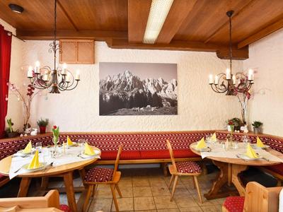 Acogedor comedor del hotel con muebles de madera, tapicería roja y montañas en la pared.