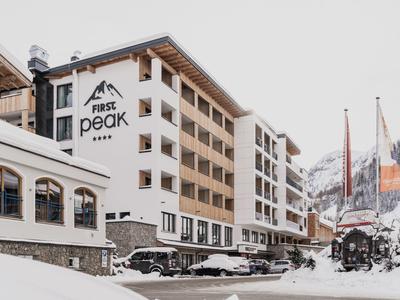 Großes Hotel namens First Peak mit verschneiter Landschaft und Bergen im Hintergrund.