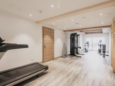 Moderner Fitnessraum mit Laufband, Gewichten und Kraftmaschinen in hellem Raum.