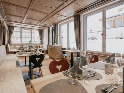 Helles Restaurant mit Holzmöbeln, herzförmigen Stühlen und eingedeckten Tischen mit Aussicht.