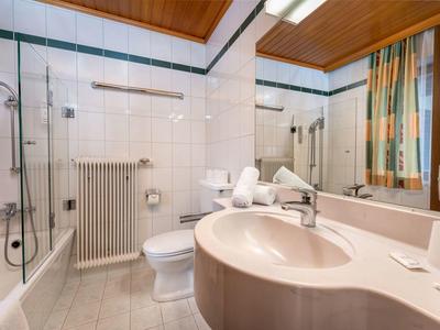 Moderne badkamer met wastafel, toilet, douche en grote spiegel.