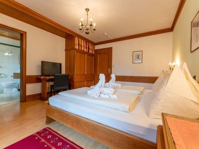 Lichte hotelkamer met twee eenpersoonsbedden, houten decor en open deur naar badkamer.