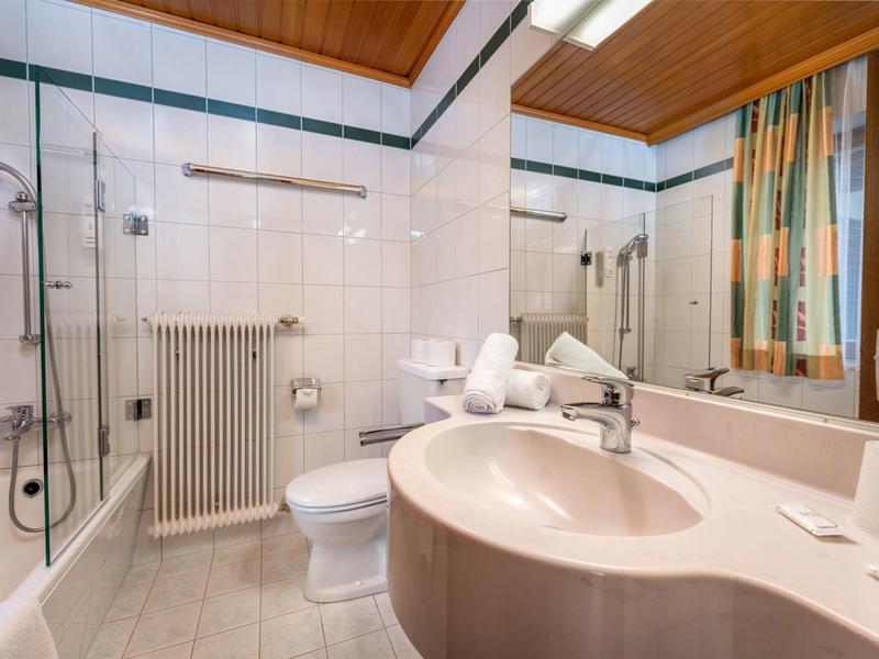Moderne badkamer met wastafel, toilet, douche en grote spiegel.