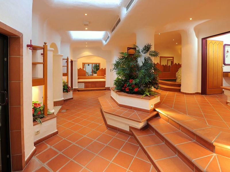 Lichte hotelentree met trap, planten en betegelde vloer.