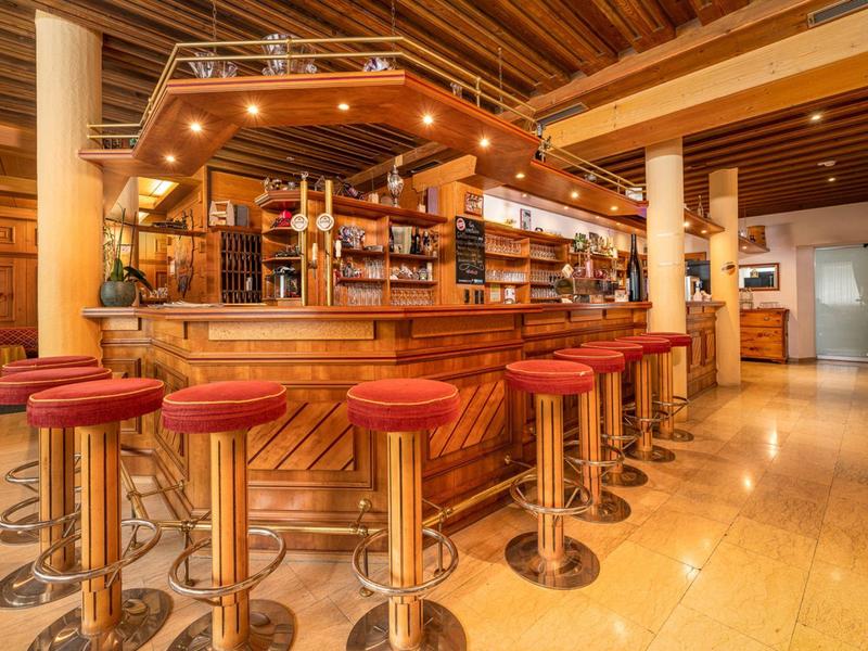 Bar met rode krukken en houten balie in een warm verlicht hotel.