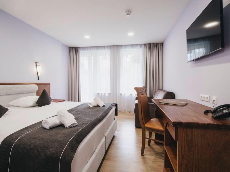 Chambre d'hôtel moderne avec lit double, bureau et télévision.