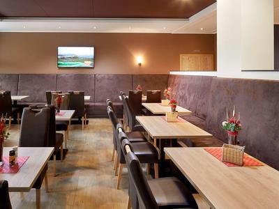 Modern restaurant with wood and leather furniture and small flower pots on tables.